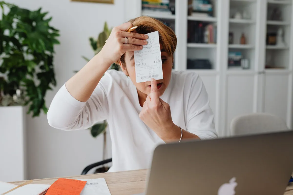 Bewoner bekijkt geschrokken een rekening aan het bureau