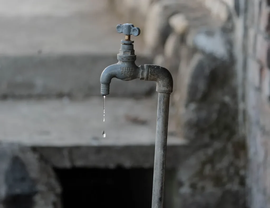 Druppelende metalen kraan aan een muur