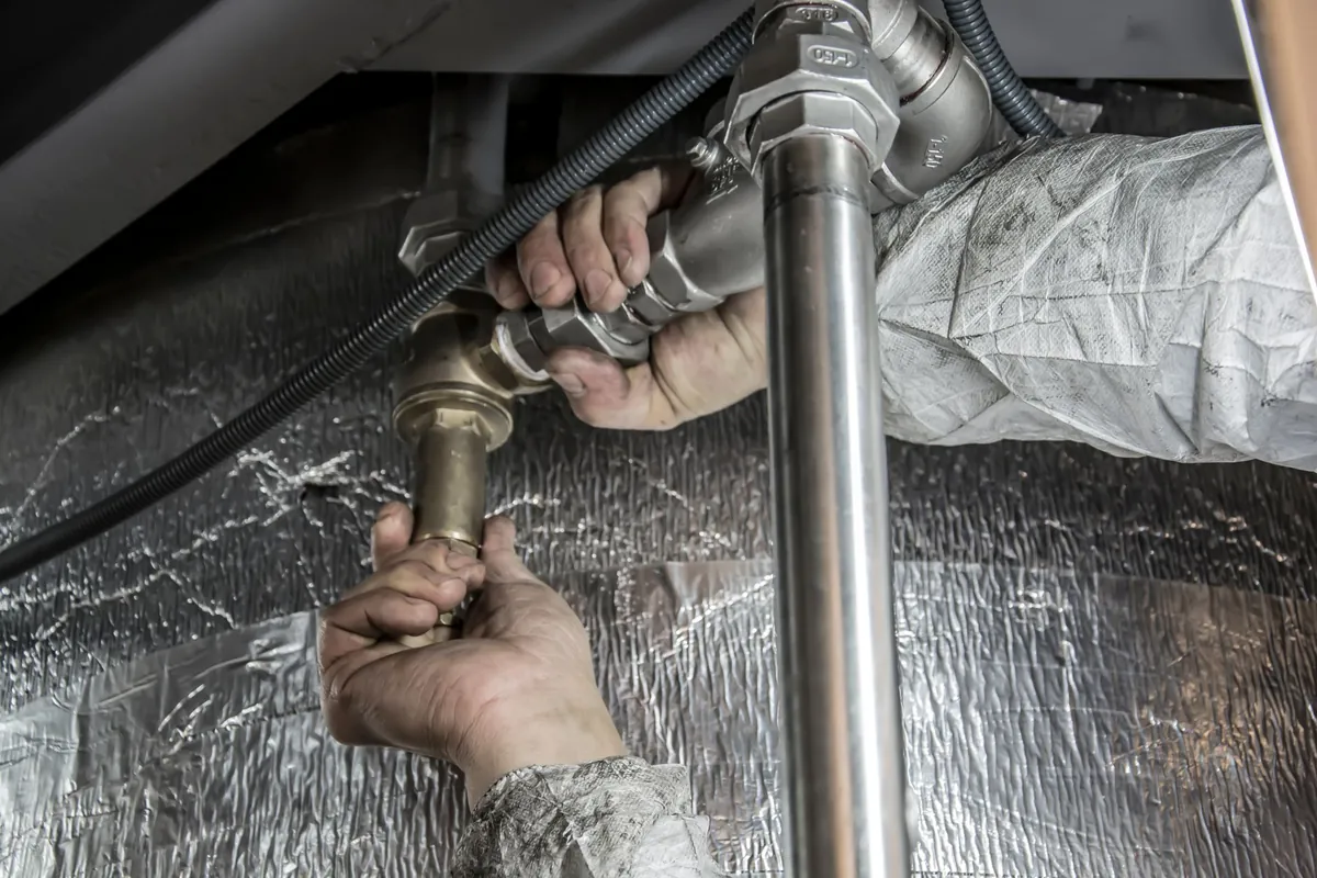 Handen draaien een koppeling vast op een geïsoleerde waterleiding