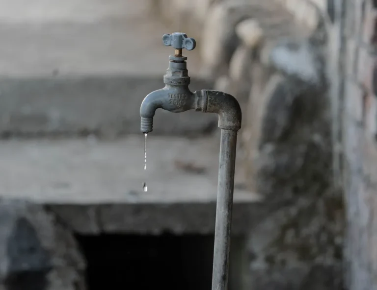Druppelende metalen kraan aan een muur